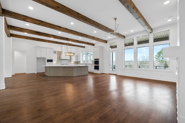 unfurnished living room with ceiling fan, sink, dark hardwood / wood-style flooring, and beam ceiling