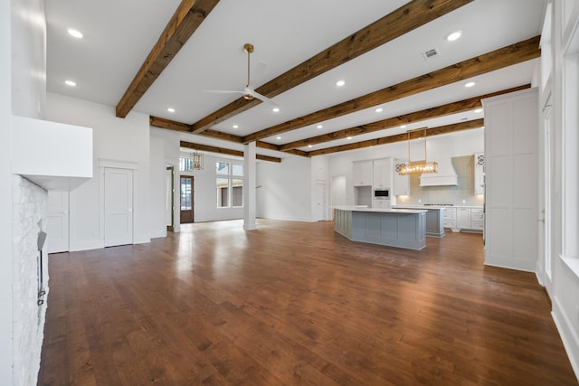 unfurnished living room with ceiling fan, dark hardwood / wood-style flooring, and beamed ceiling