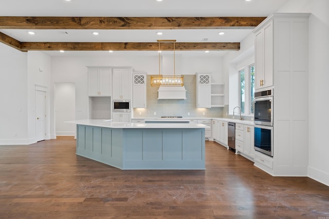 kitchen featuring hanging light fixtures, appliances with stainless steel finishes, white cabinets, and a large island