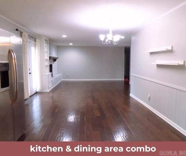 unfurnished living room featuring a brick fireplace, a notable chandelier, and dark hardwood / wood-style flooring