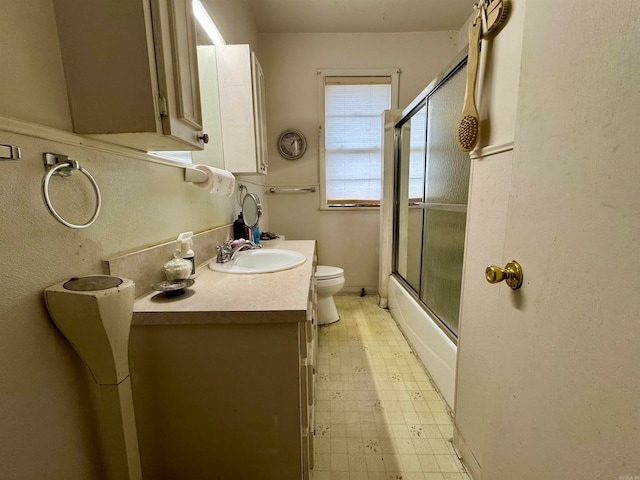 full bathroom with vanity, toilet, and combined bath / shower with glass door