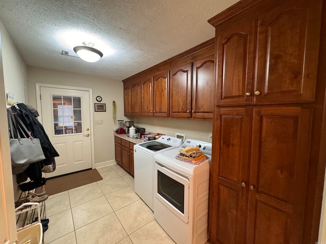 laundry area featuring cabinets, washer and dryer, light tile patterned floors, and a textured ceiling