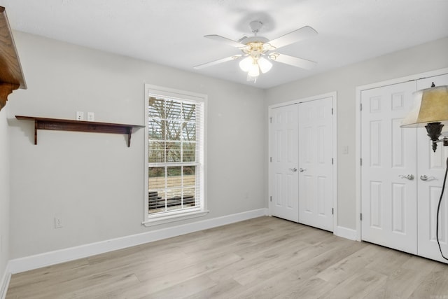 unfurnished bedroom featuring multiple closets, ceiling fan, and light hardwood / wood-style floors