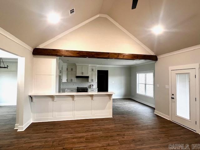 kitchen with dark hardwood / wood-style flooring, kitchen peninsula, white cabinets, ornamental molding, and a breakfast bar