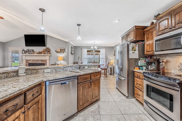 kitchen with stainless steel appliances, backsplash, sink, light tile patterned flooring, and decorative light fixtures