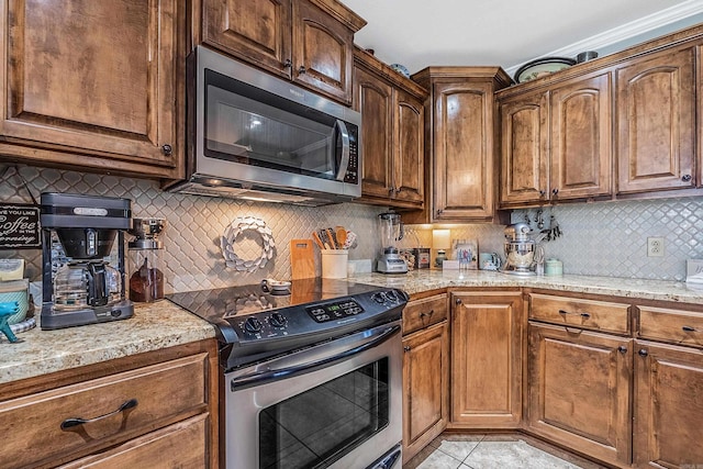 kitchen with appliances with stainless steel finishes, light stone counters, backsplash, and light tile patterned floors