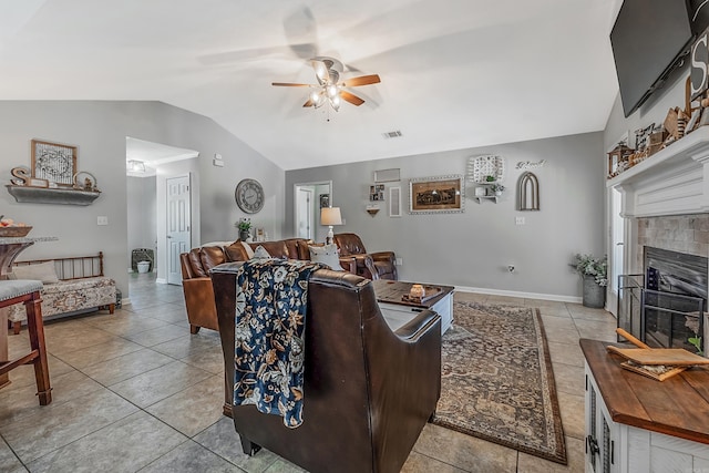 tiled living room with ceiling fan, lofted ceiling, and a tile fireplace