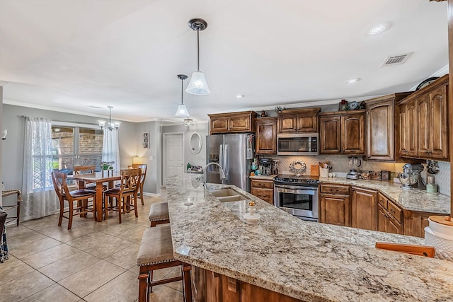 kitchen featuring appliances with stainless steel finishes, a kitchen bar, sink, crown molding, and decorative light fixtures