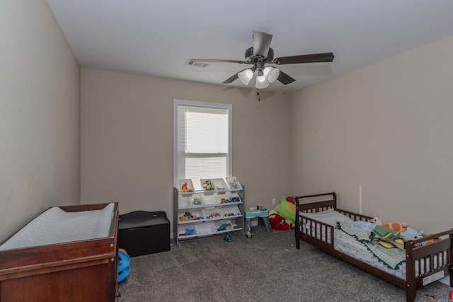 bedroom featuring dark colored carpet, a crib, and ceiling fan