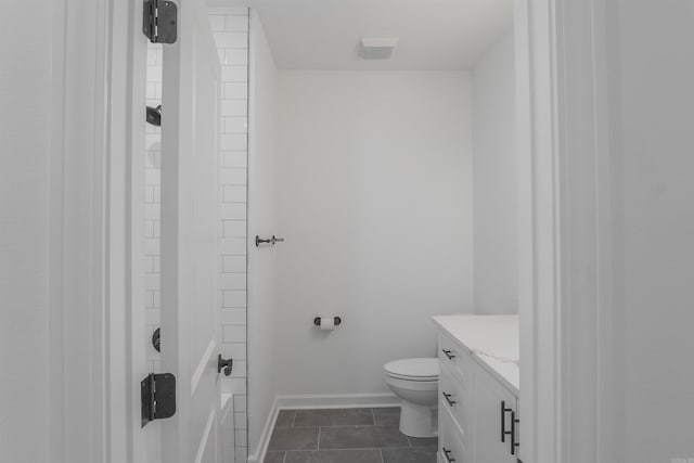 bathroom with toilet, vanity, and tile patterned flooring