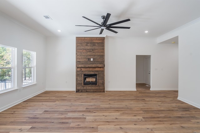 unfurnished living room with light hardwood / wood-style floors, crown molding, a large fireplace, and ceiling fan