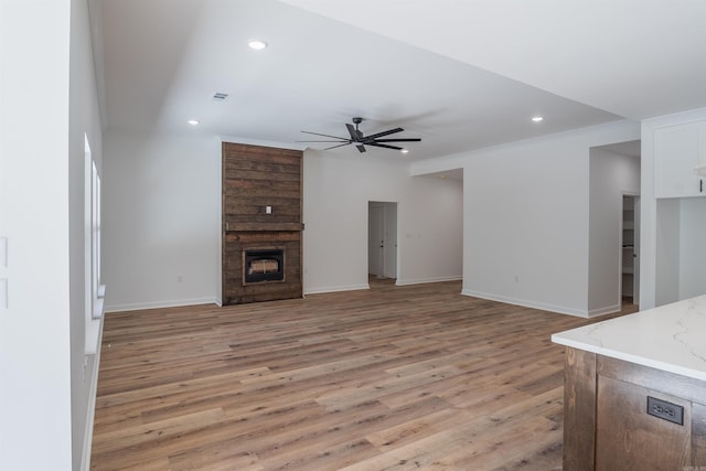 unfurnished living room with ceiling fan, light wood-type flooring, and a fireplace