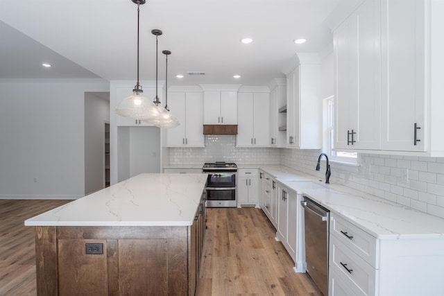 kitchen featuring a kitchen island, hanging light fixtures, stainless steel appliances, white cabinets, and light hardwood / wood-style floors