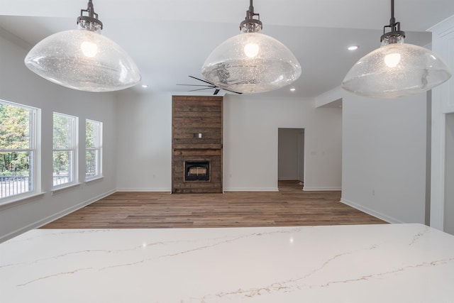 unfurnished living room with a large fireplace, wood-type flooring, and ceiling fan