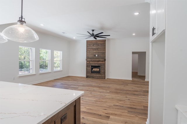 kitchen with light hardwood / wood-style floors, white cabinetry, light stone countertops, and hanging light fixtures