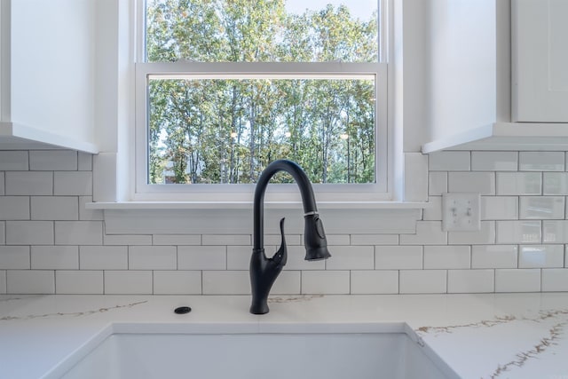 details with white cabinetry, decorative backsplash, light stone counters, and sink