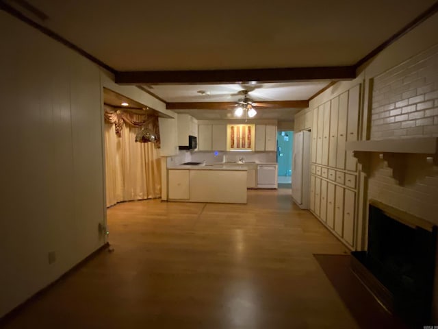 kitchen featuring white appliances, light wood-type flooring, a brick fireplace, beamed ceiling, and white cabinets