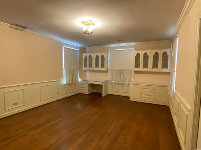 empty room featuring built in desk, crown molding, and dark hardwood / wood-style flooring