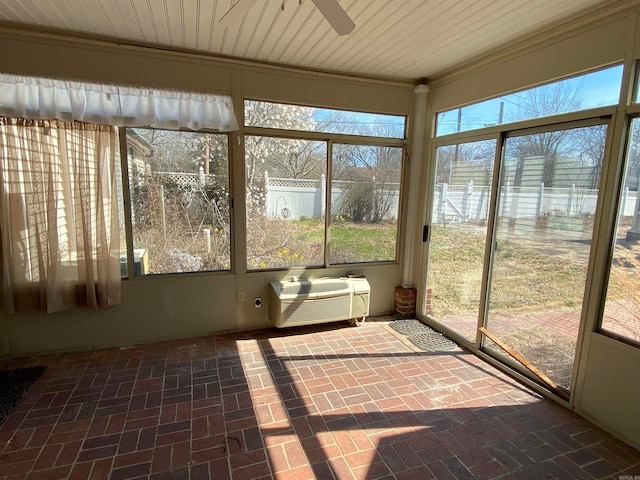 unfurnished sunroom with ceiling fan, a wealth of natural light, and a wall mounted air conditioner