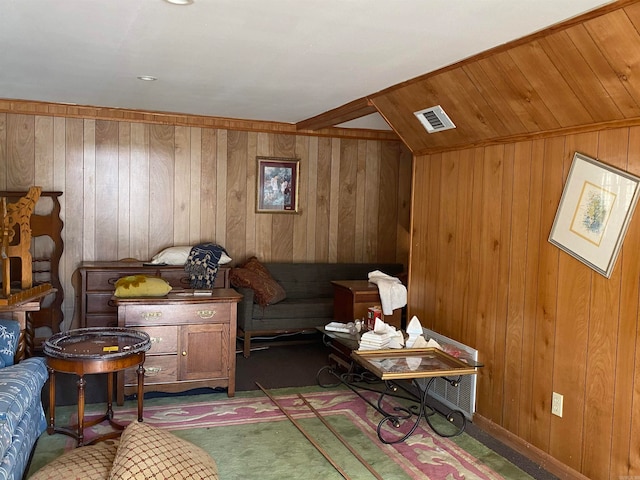 sitting room with wood walls, lofted ceiling, and dark colored carpet