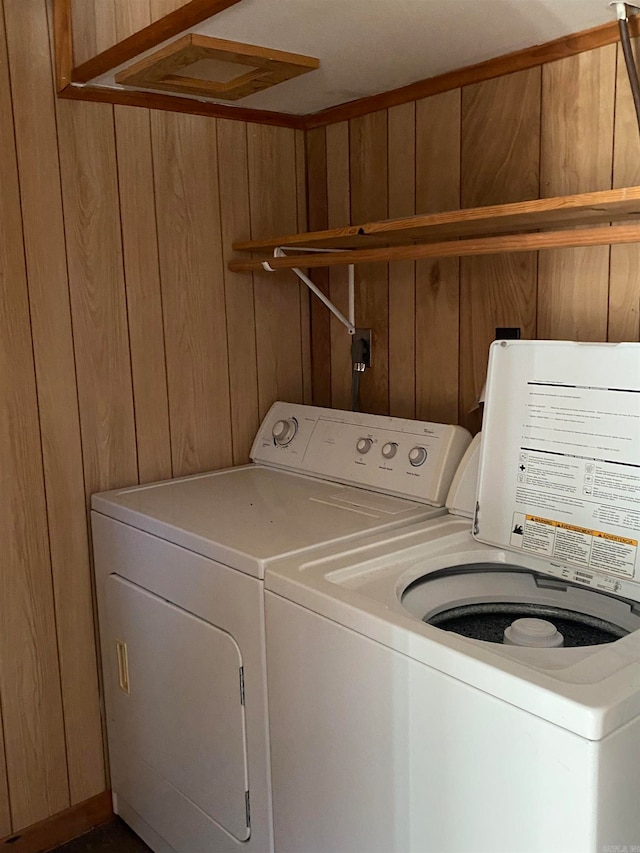 laundry area with wood walls and separate washer and dryer