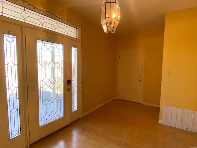 foyer with light parquet floors and an inviting chandelier