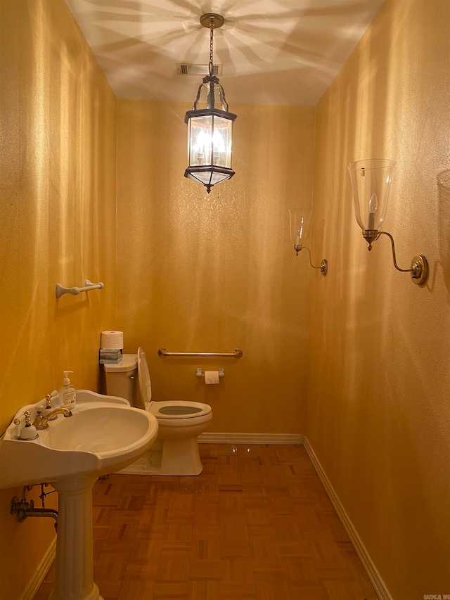 bathroom featuring toilet, sink, and parquet floors