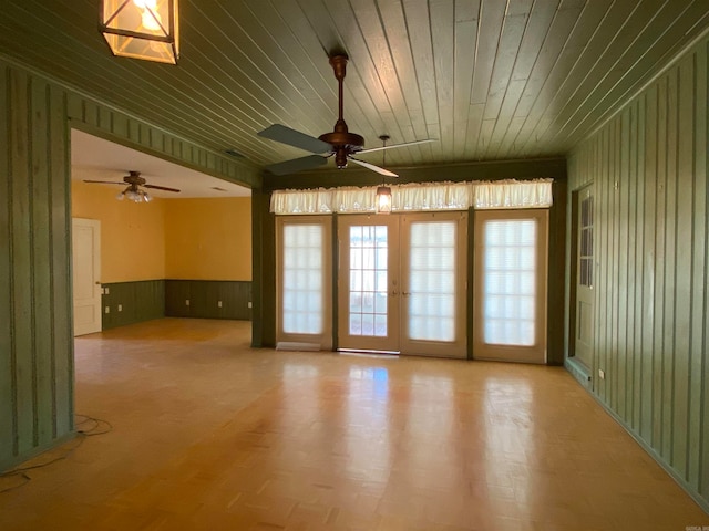 spare room with french doors, wood ceiling, wooden walls, and ceiling fan