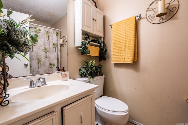 bathroom with vanity, toilet, and a textured ceiling