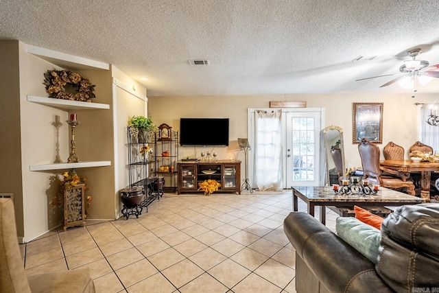 living room featuring a textured ceiling, light tile patterned floors, and ceiling fan