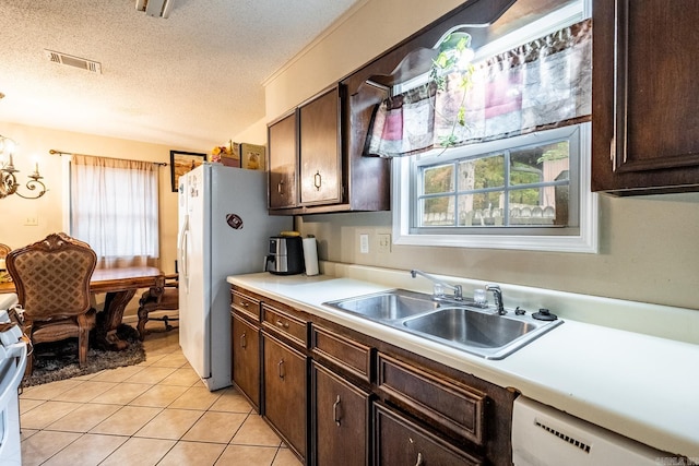 kitchen featuring dark brown cabinets, a textured ceiling, sink, and light tile patterned floors