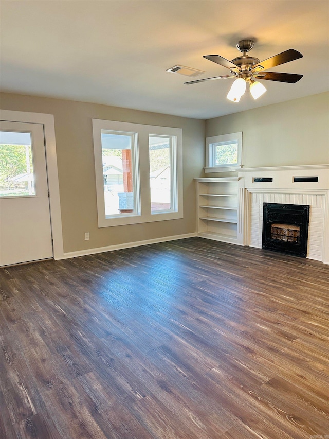 unfurnished living room featuring dark wood-type flooring, ceiling fan, and a brick fireplace