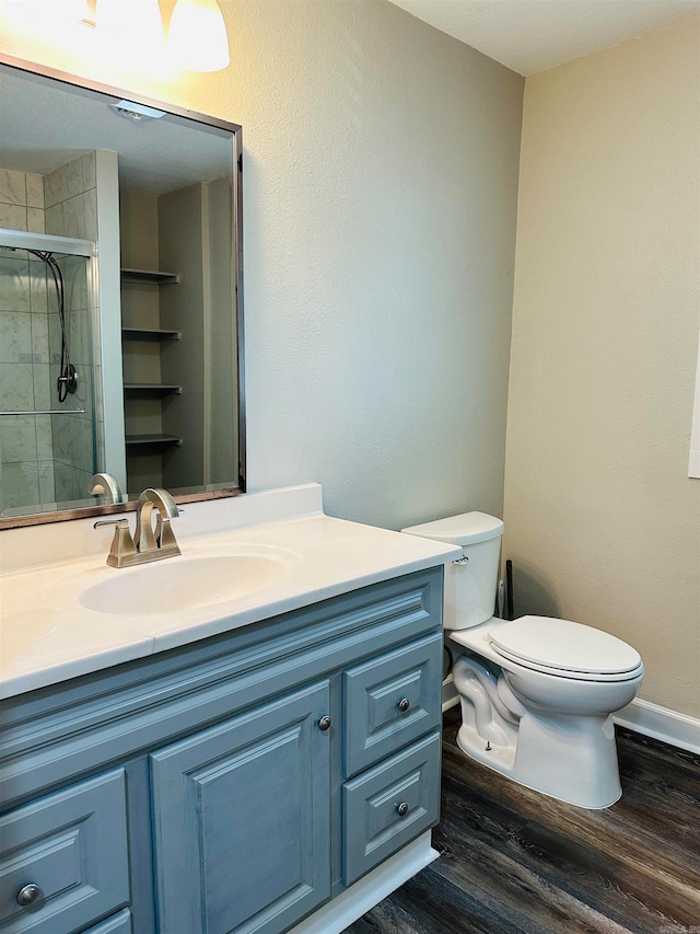 bathroom featuring toilet, vanity, wood-type flooring, and a shower with door