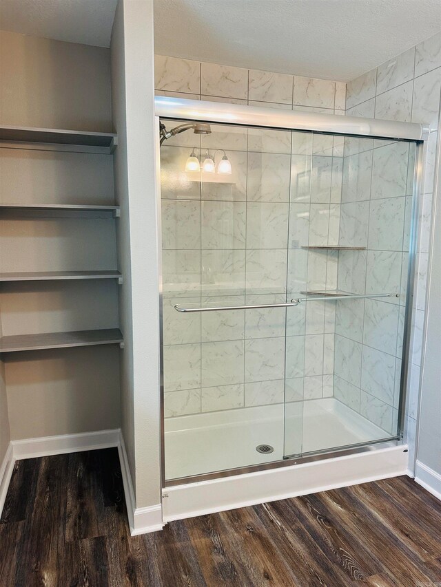 bathroom featuring a textured ceiling, a shower with shower door, and wood-type flooring