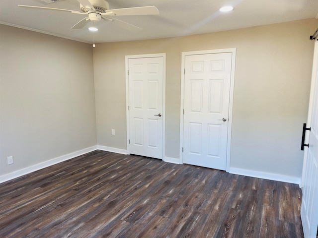 unfurnished bedroom featuring dark wood-type flooring, two closets, and ceiling fan