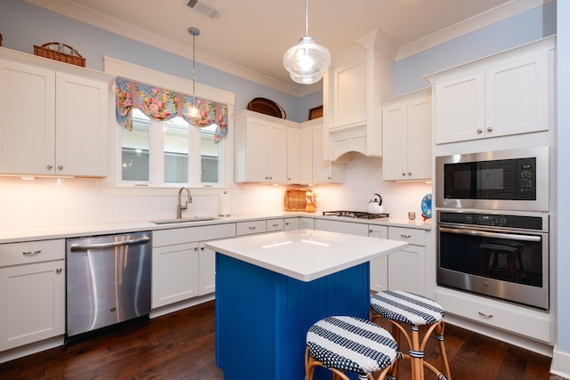 kitchen featuring stainless steel appliances, dark wood-type flooring, sink, decorative light fixtures, and a center island