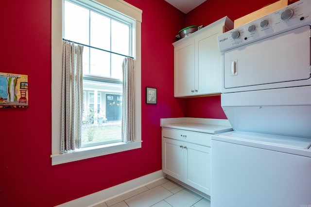 laundry area with stacked washing maching and dryer, cabinets, and light tile patterned floors