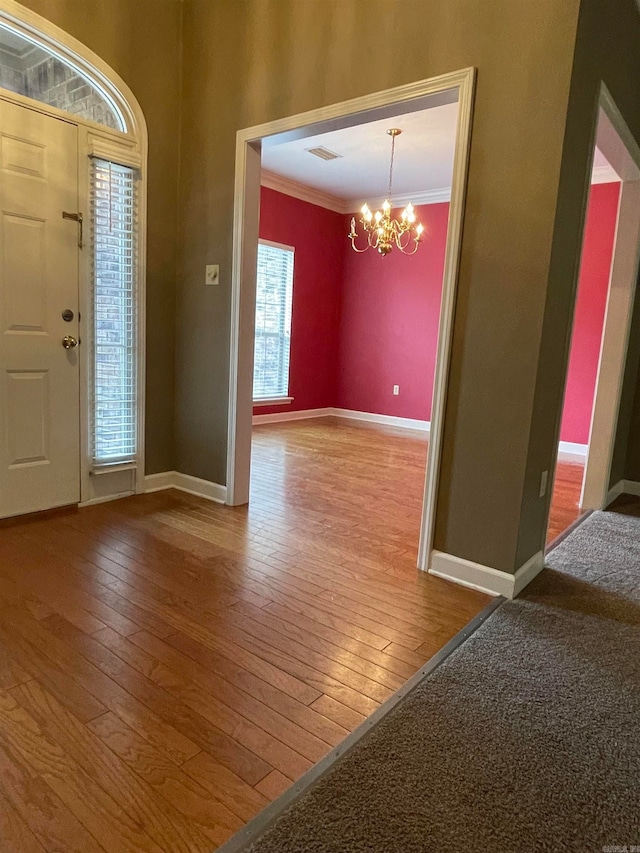 foyer entrance with a chandelier, hardwood / wood-style flooring, and crown molding