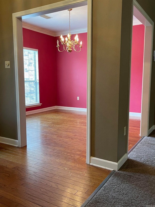 unfurnished dining area with a chandelier, hardwood / wood-style flooring, and ornamental molding