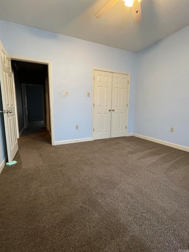 unfurnished bedroom featuring dark colored carpet, ceiling fan, and a closet