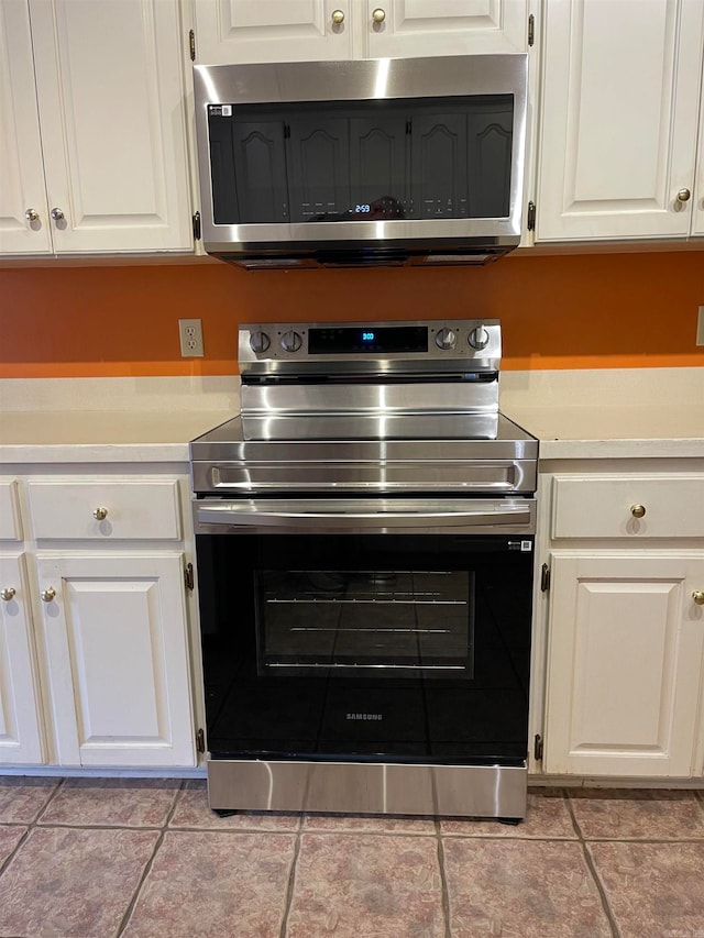 kitchen with white cabinetry, light tile patterned floors, and stainless steel appliances