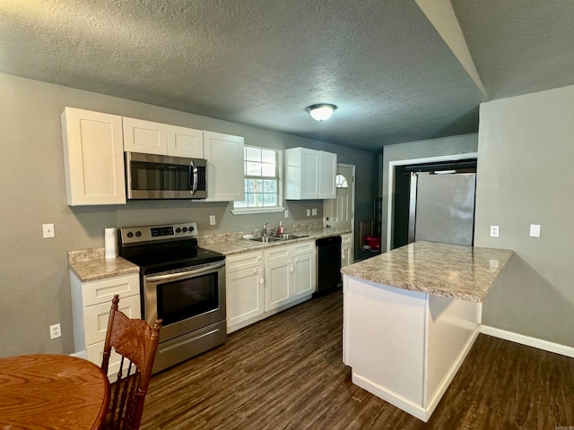 kitchen with light stone countertops, appliances with stainless steel finishes, sink, white cabinets, and dark wood-type flooring