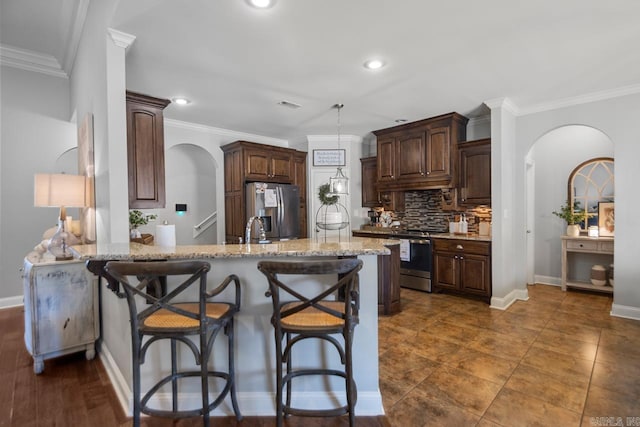 kitchen featuring light stone countertops, kitchen peninsula, stainless steel appliances, ornamental molding, and a breakfast bar