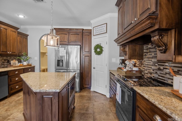 kitchen with a kitchen island, backsplash, light stone countertops, pendant lighting, and appliances with stainless steel finishes