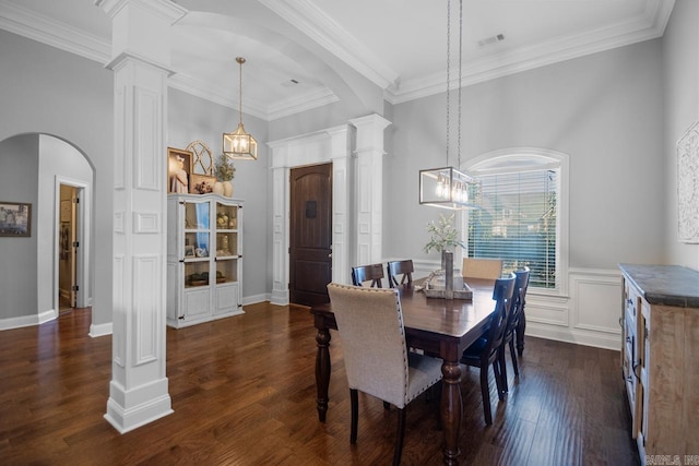 dining area with dark wood-type flooring, crown molding, decorative columns, and a high ceiling