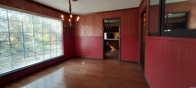 unfurnished dining area featuring a chandelier and dark hardwood / wood-style flooring