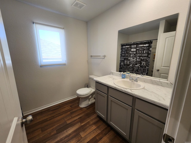 bathroom with toilet, hardwood / wood-style floors, walk in shower, and vanity