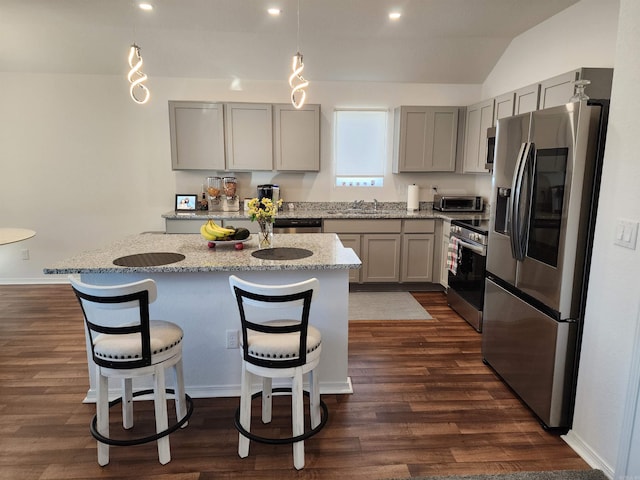 kitchen with light stone countertops, lofted ceiling, dark wood-type flooring, and appliances with stainless steel finishes