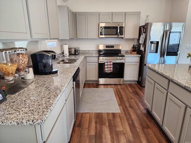 kitchen with gray cabinetry, sink, dark hardwood / wood-style flooring, stainless steel appliances, and light stone counters