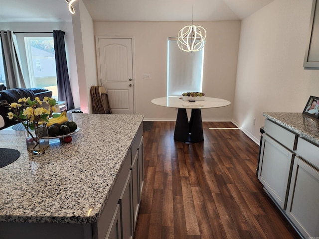 kitchen featuring a kitchen island, dark hardwood / wood-style floors, gray cabinetry, light stone countertops, and decorative light fixtures